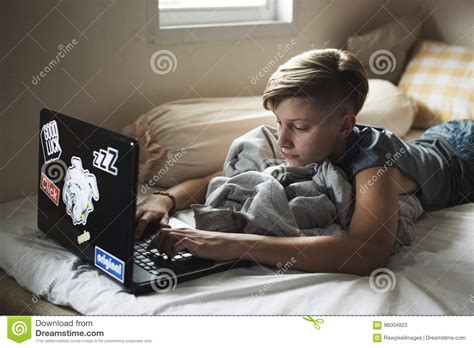 jonge kaukasische jongen die gebruikend computerlaptop op bed liggen stock afbeelding image