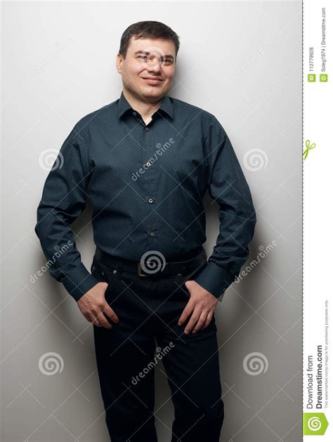 Man Portrait Dressed In Dark Shirt And Black Pants Over Gray Background