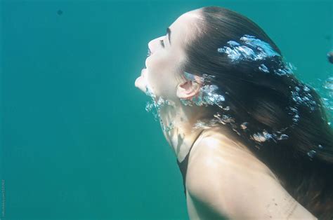 Brunette Woman Swimming Forward With Bubbles By Stocksy Contributor