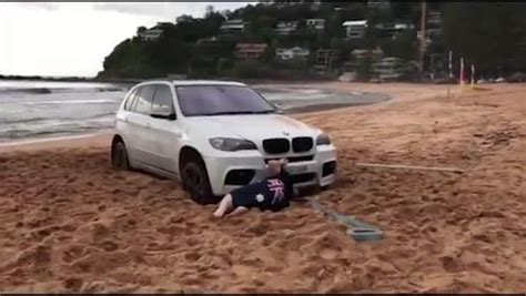 car stuck on home and away beach palm beach with driver trying to dig