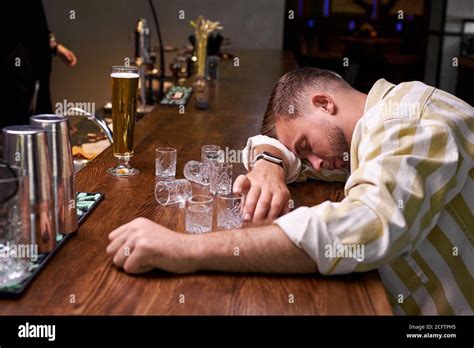 very drunk man sleep in the bar sits alone with empty glasses of