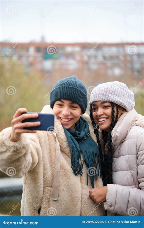 happy dominican lesbian couple taking a selfie with phone at street in