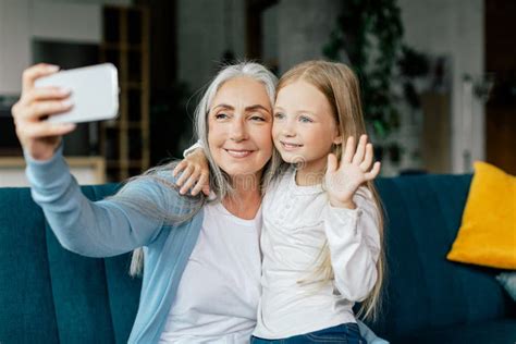 Glad Caucasian Small Girl And Retired Granny Waving Hand In Smartphone