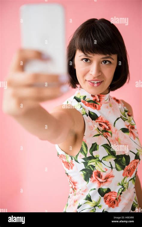 Hispanic Woman Wearing Floral Dress Posing For Cell Phone Selfie Stock