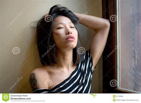 Beautiful Sensual Asian Woman Posing Thoughtful At Window Stock Image