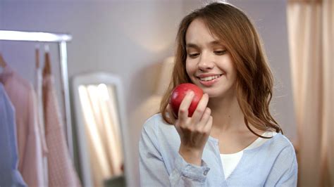portrait of cheerful woman eating red apple at morning close up of