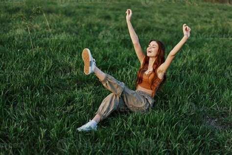 A Woman Lies On The Green Grass In The Park With Her Legs Up And Having