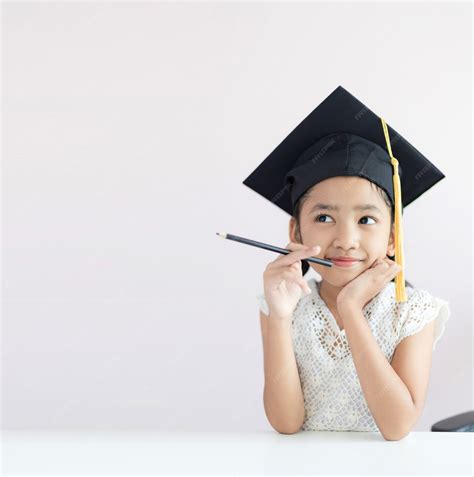 premium photo portrait  asian girl  wearing graduate hat holding pencil sitting