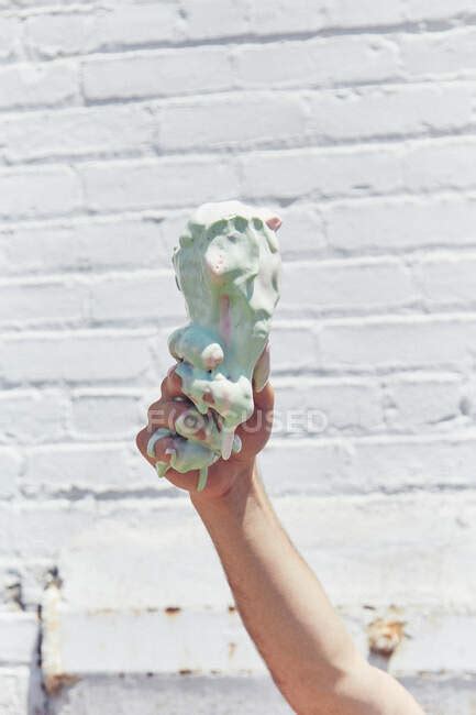 Man Holding Up Melting Dripping Ice Cream Cone Close Up Of Hand