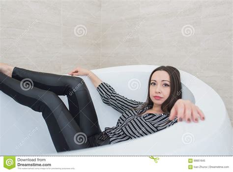 the brunette girl lies in a bathtub with a calm and peaceful expression