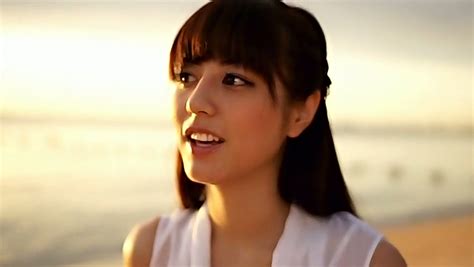 slim asian girl yumi sugimoto walks on a beach wearing white dress