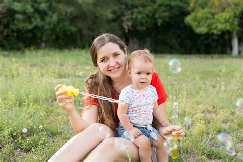 premium photo happy mother and daughter blowing bubbles in the park