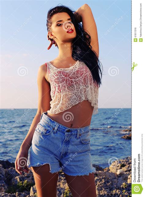 beautiful woman wears a top with jeans shorts and posing