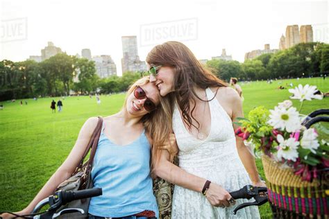 Smiling Romantic Lesbian Couple With Bicycles On Grassy