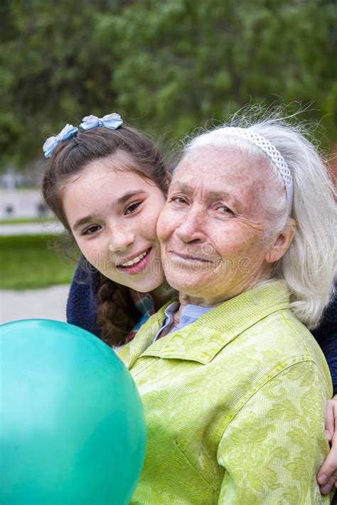 cute teenage girl is hugging her beautiful smiling granny in cheek