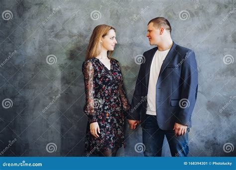 Elegant And Happy Couple Touching Each Other By Hands Posing At Camera