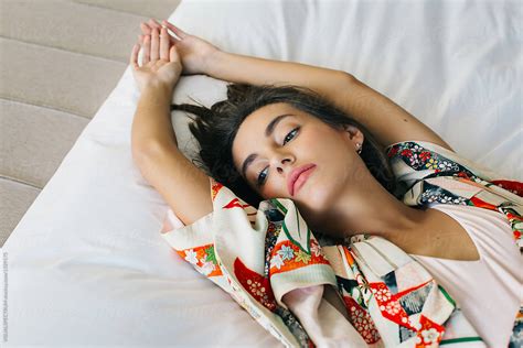 overhead closeup of beautiful brunette in japanese kimono lying on bed