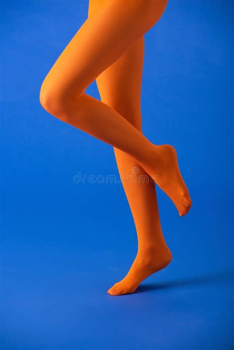 View Of Woman In Bright Orange Tights Posing On Blue Stock Image