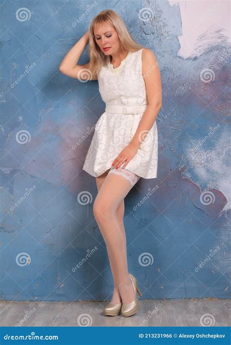 Blonde Legged Photomodel In White Minidress And White Stockings Posing