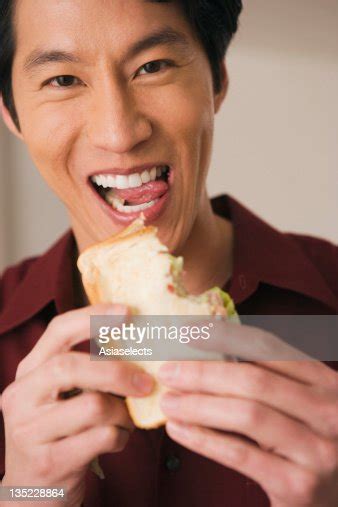 Portrait Of A Young Man Eating Sandwich And Smiling High Res Stock