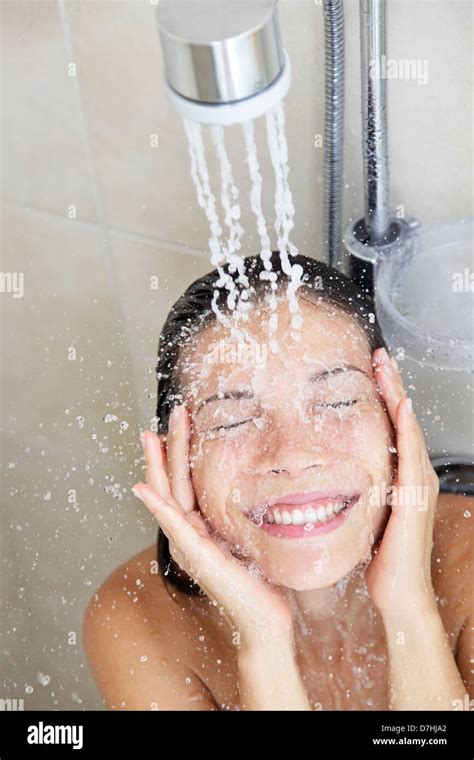 shower woman washing face in while showering with happy smile and water