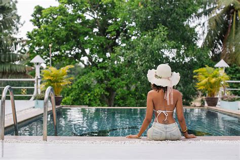 woman sitting near swimming pool pormosuno