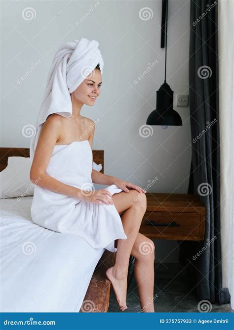 Woman Sitting On Bed After Shower With Wet Hair With Towel On Head In