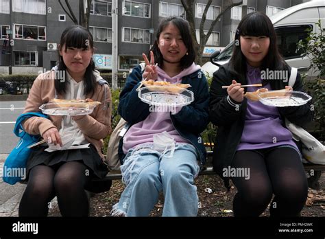 Three Japanese Girls Eating Junk Food On Omotesando Street Tokyo