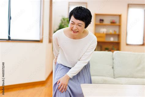 家で膝の痛みに苦しんでいる成熟した日本人女性 Photos Adobe Stock