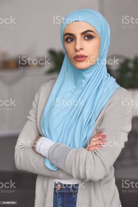 beautiful serious muslim woman in hijab standing with crossed arms and