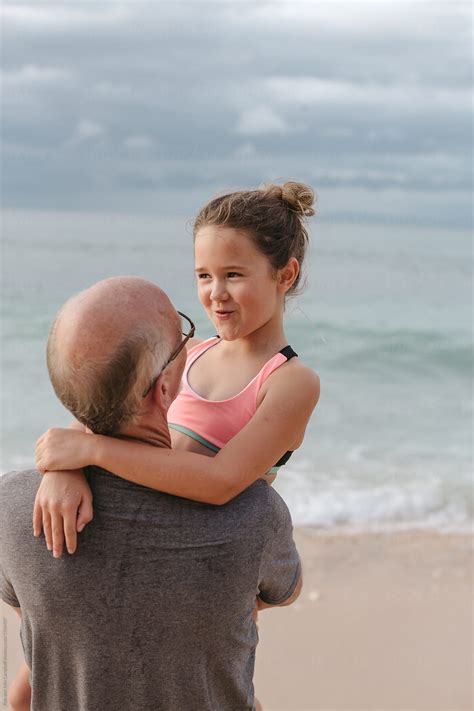 active happy grandpa having fun with granddaughter on beach vac by