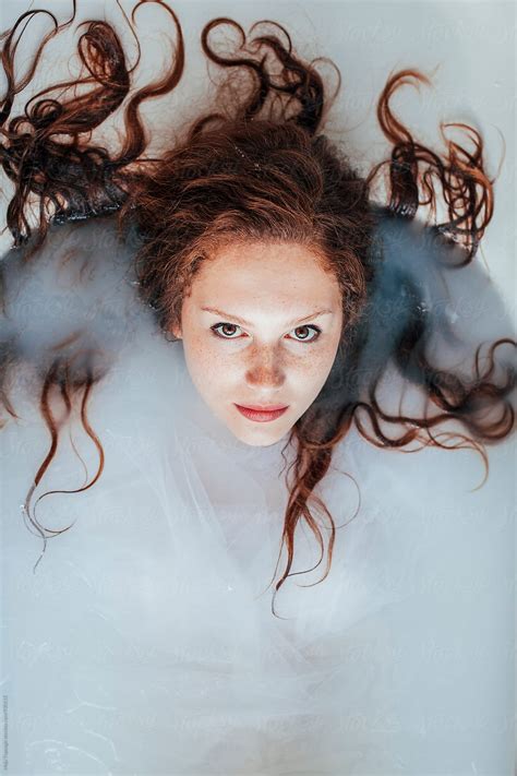 portrait of a beautiful redhead with freckles having a milk bath