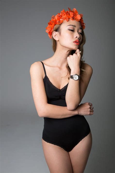 A Woman In A Black Bodysuit With An Orange Flower Crown On Her Head Is