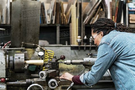 Woman Wearing Safety Glasses Standing In A Metal Workshop