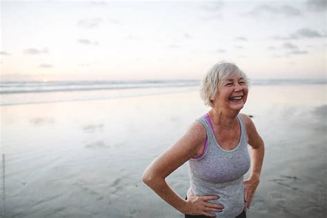 vibrant mature woman enjoying herself on the beach at sunset by