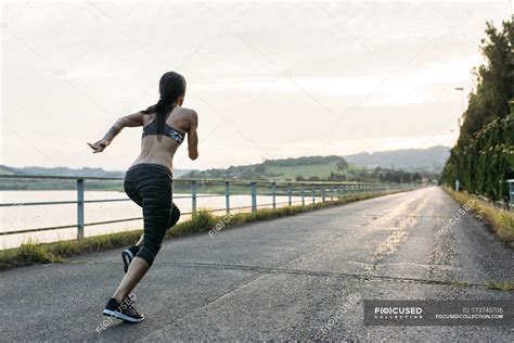 view  young woman running outdoors dark hair training stock