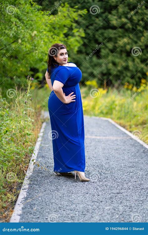 Plus Size Fashion Model In Blue Dress With A Deep Neckline Outdoors