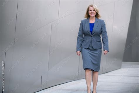 older female executive corporate business woman in suit walking outside