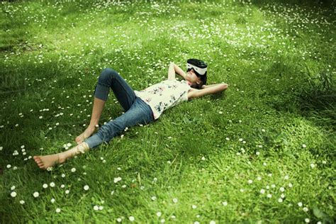 Mixed Race Girl Laying In Grass Wearing Virtual Reality Goggles Stock