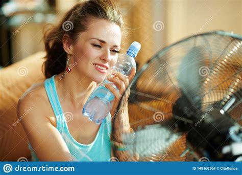 Hot Woman With Bottle Of Cold Water Using Electric Metallic Fan Stock