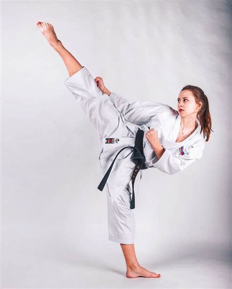 A Woman Is Doing Karate On A White Background With Her Leg Up In The Air