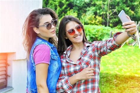 two joyful fanny pretty girls having fun taking a selfie on mobile