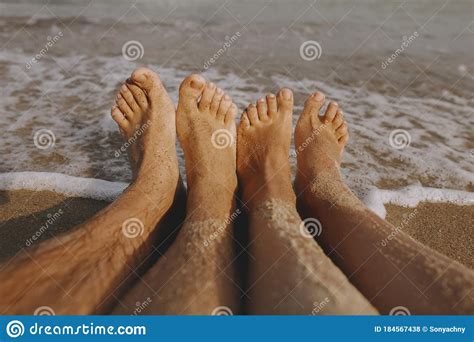 couple wet feet in sand close up on sunny beach with waves