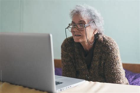 funny grandma with two pairs of glasses looking at laptop by nemanja