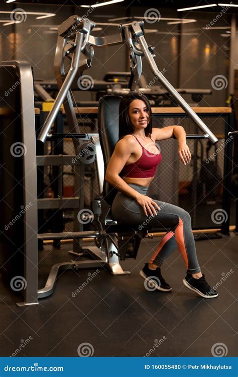 Fitness Brunette Girl Is Sitting On Training Apparatus And Posing Stock