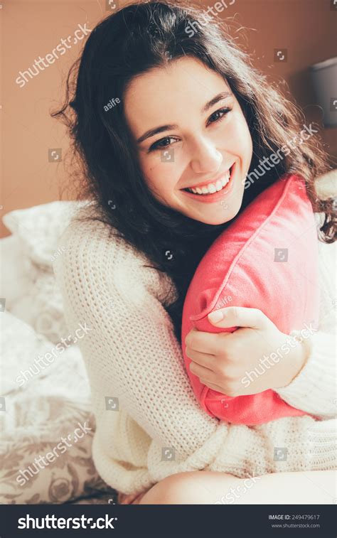 cute and happy teen girl hugging a pink cushion in bed