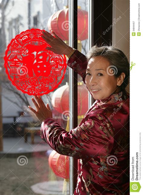 Mature Women Posting A Chinese Cut Paper On Window Stock