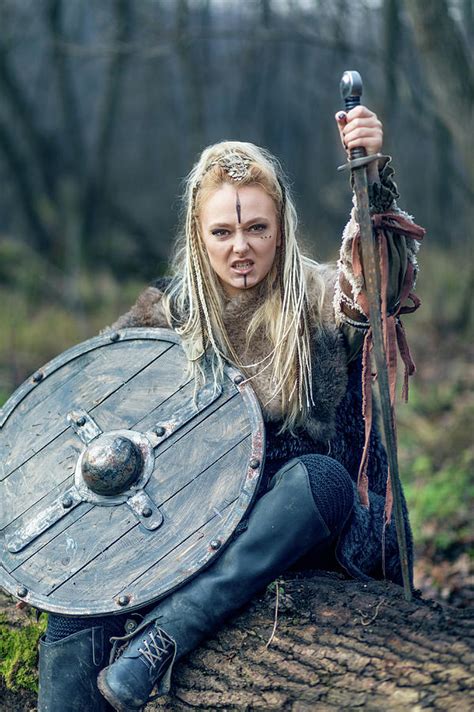 blonde viking warrior woman in forest with shield and sword in hand