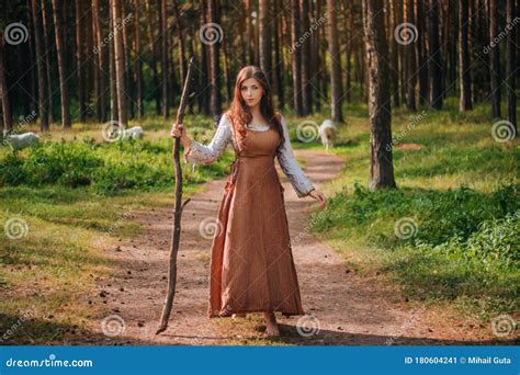 戴着中世纪牛仔服、手持棍子的年轻漂亮女人 在地上赤脚 在森林的背景下 库存图片 图片 包括有 幻想 无耻的 180604241