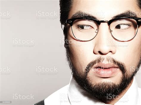 suspicious asian man with glasses and beard looking sideways stock